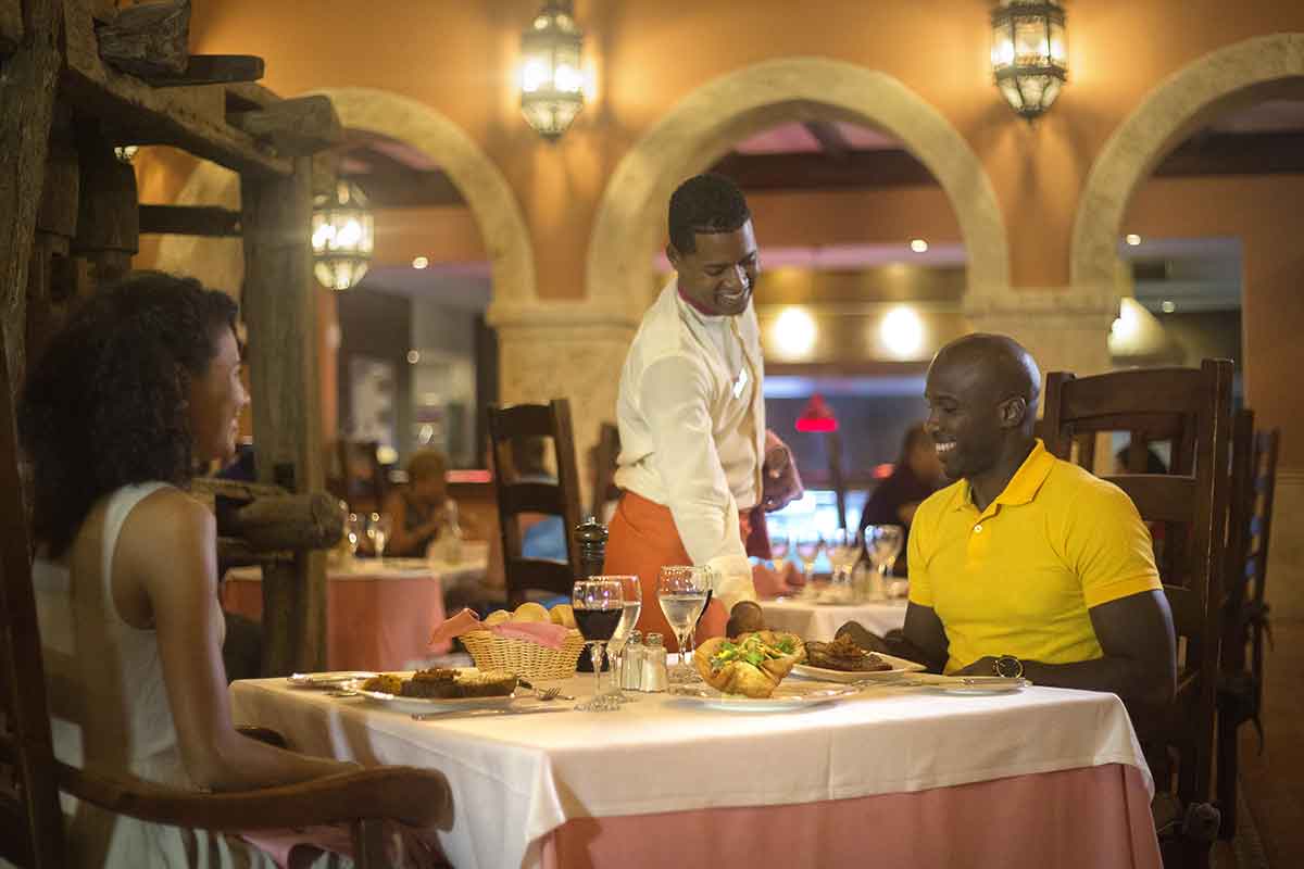 Camarero sirviendo una comida a una pareja de clientes en restaurant