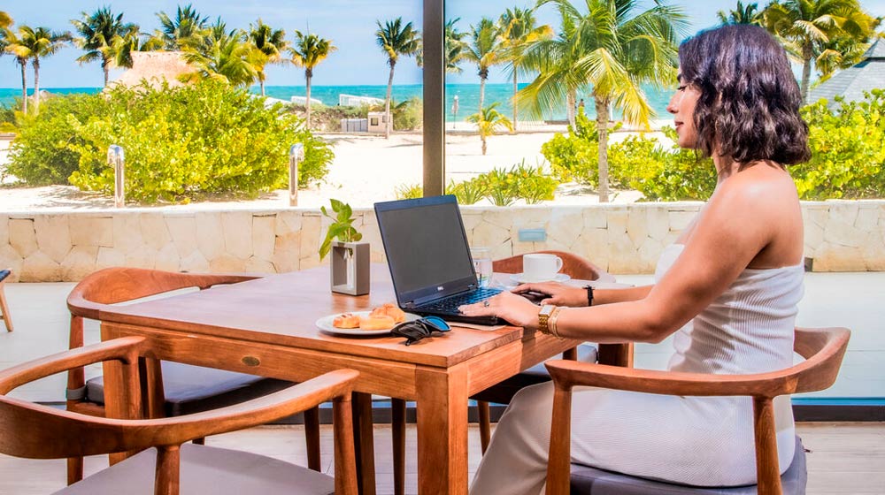 Mujer con su ordenador en la terraza de Majestic Elegance Costa Mujeres