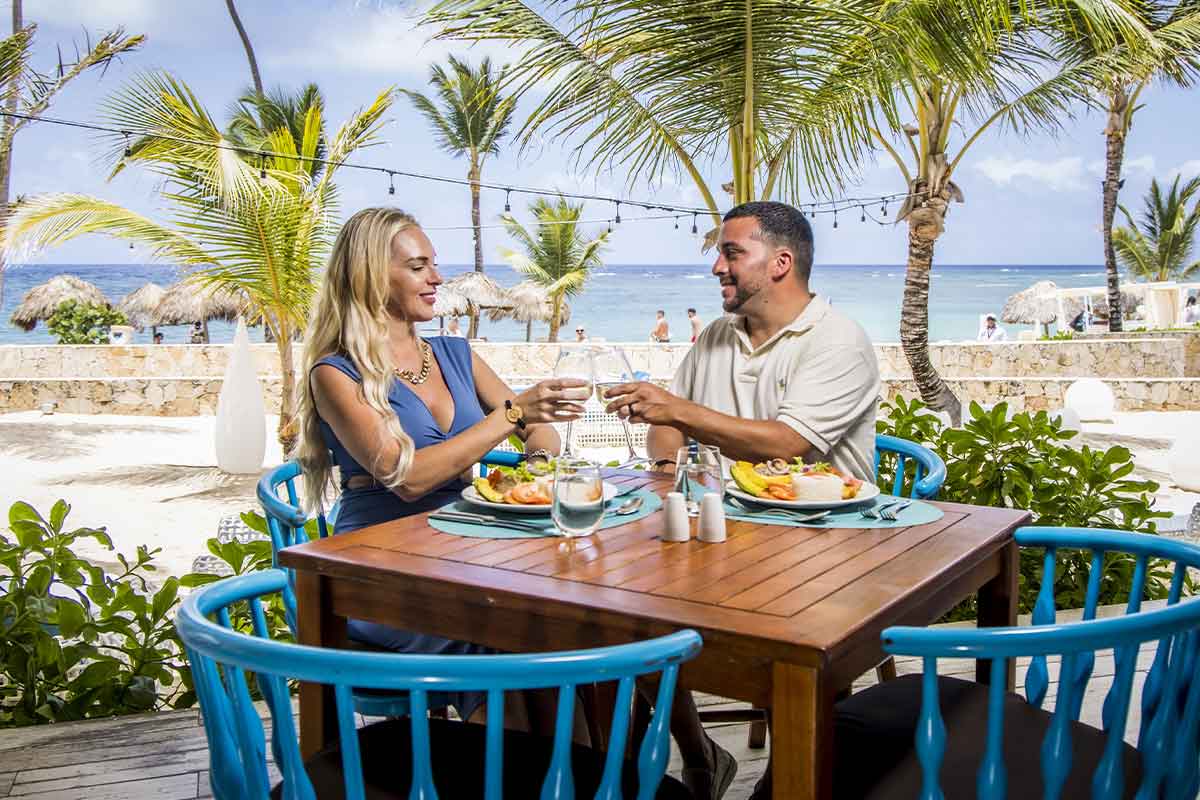 Pareja brindando en la terraza del restaurante con vistas a la playa
