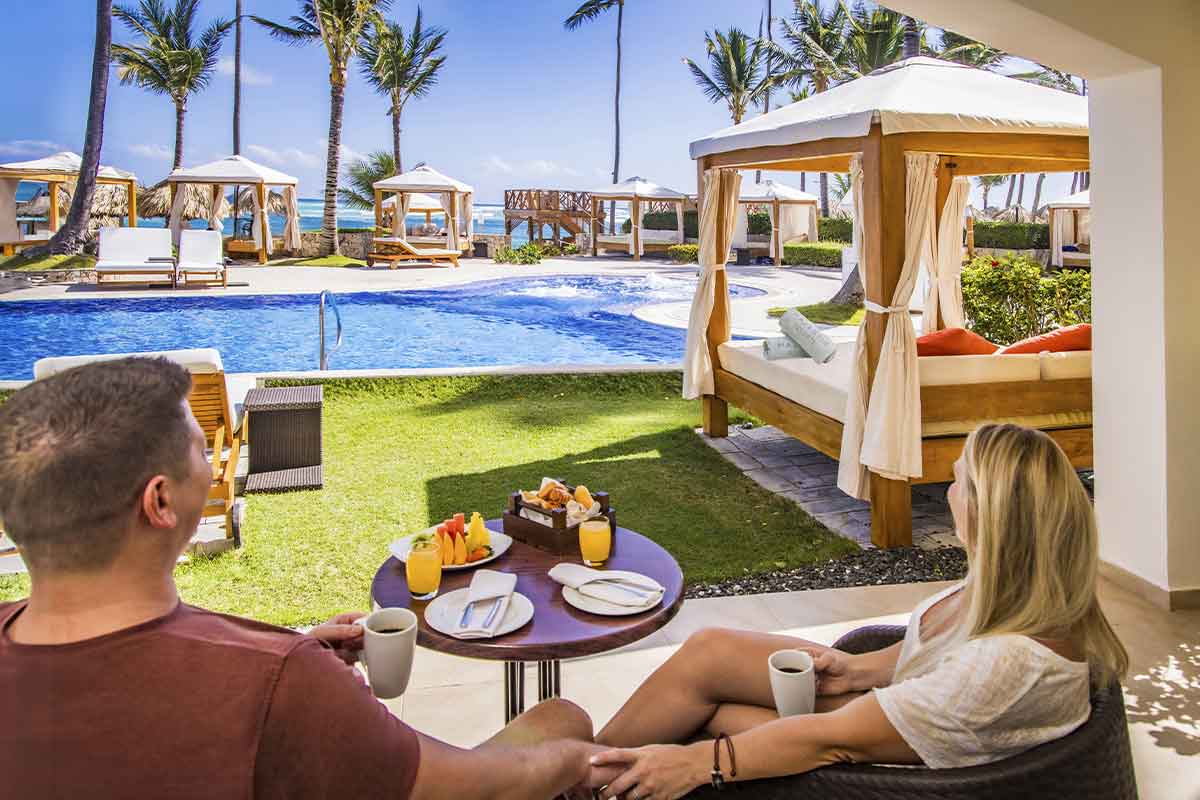 Pareja desayunando en la terraza de su habitación con vistas a la piscina