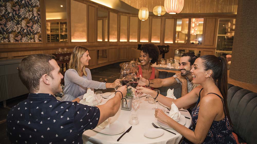 Amigos difrutando de una comida en un restaurante Majestic Elegance Costa Mujeres
