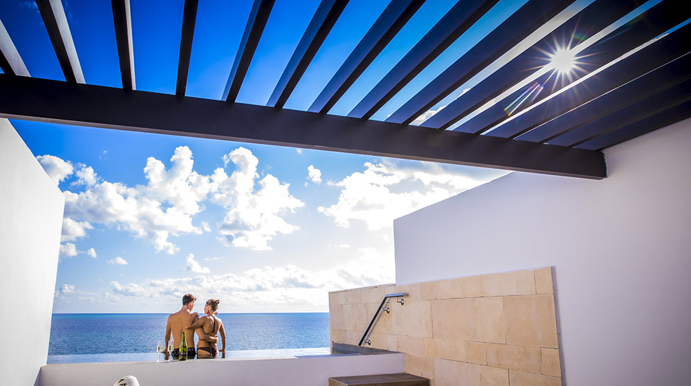 Pareja sentada en la piscina de la habitación frente al mar Majestic Elegance Costa Mujeres