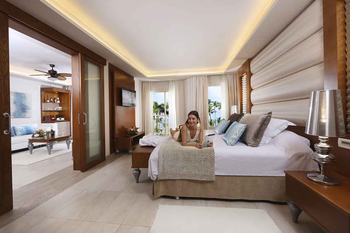 Mujer sobre gran cama en amplia y confortable habitación