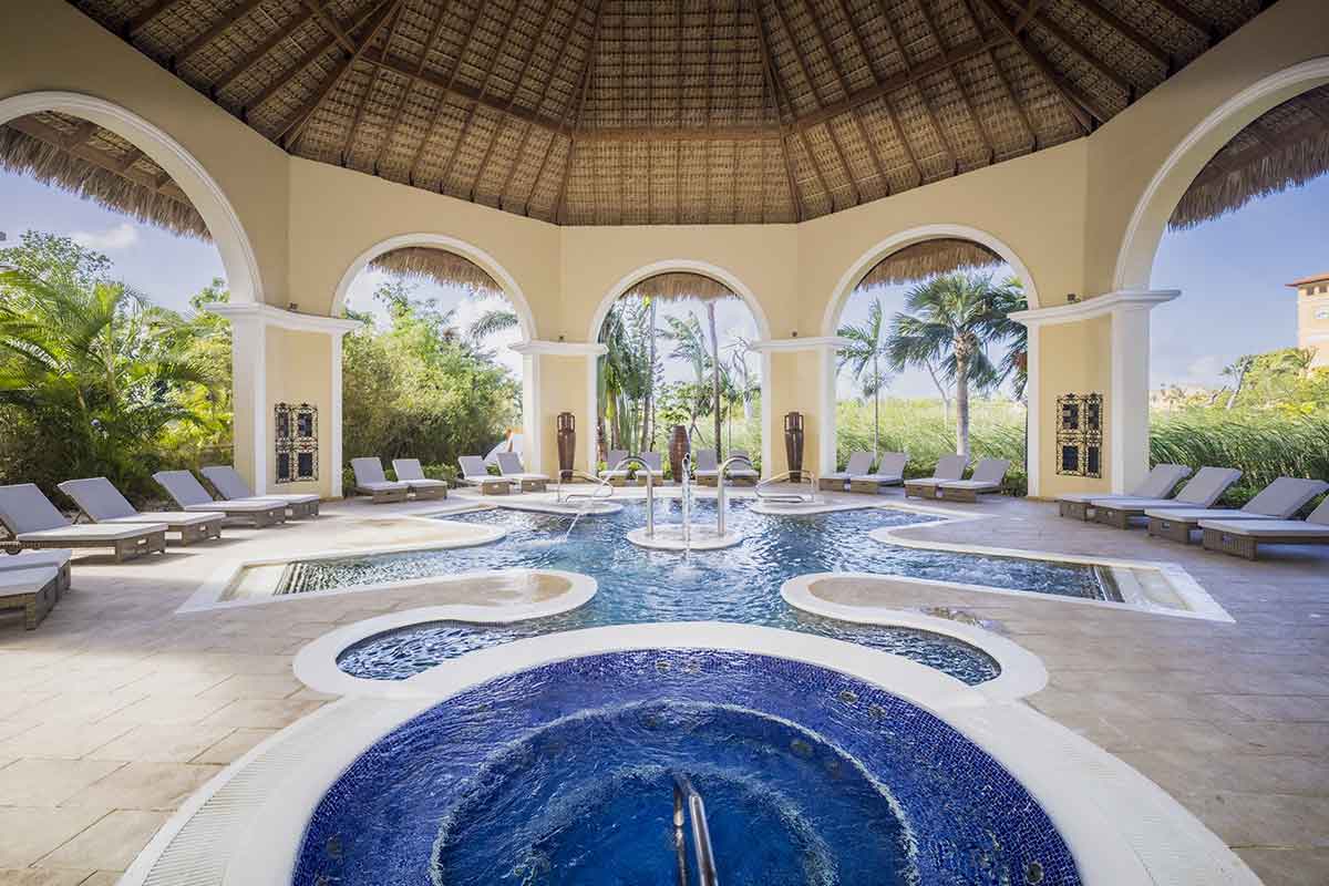 Piscina cubierta con chorros y burbujas, rodeada de hamacas y con vistas al jardín