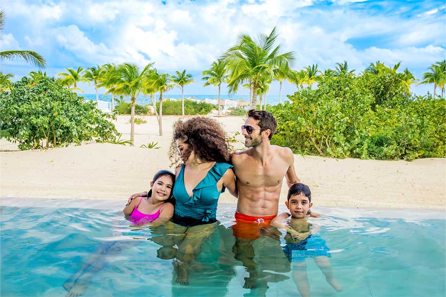 Familia tomando un baño en la playa de Majestic Elegance Costa Mujeres