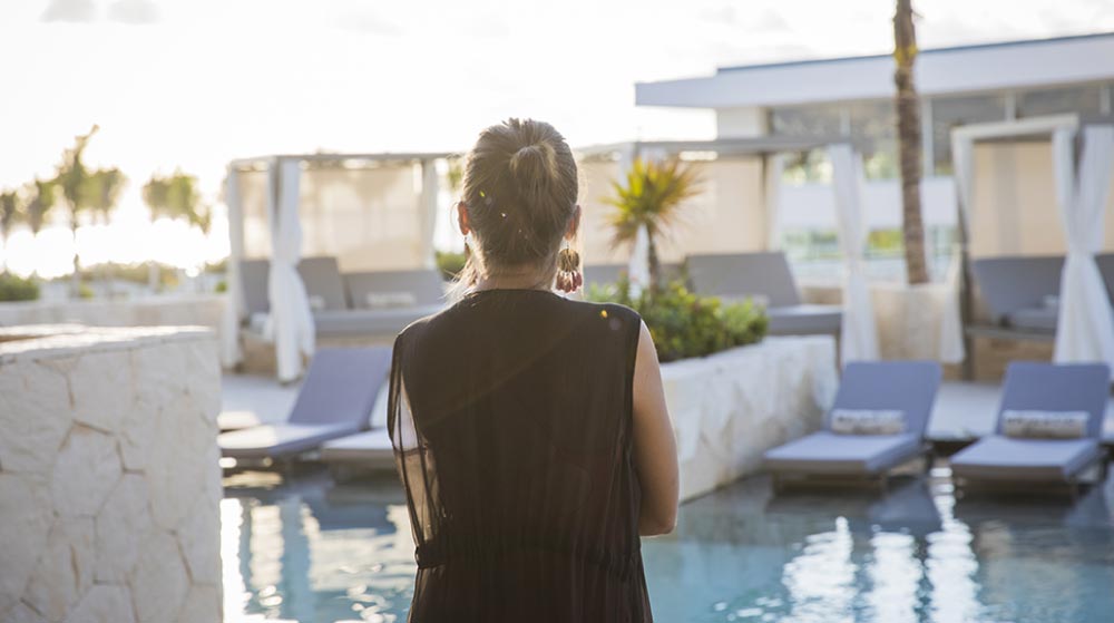 Mujer contemplando la piscina Majestic Elegance Costa Mujeres